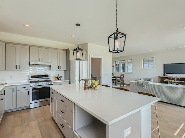 kitchen featuring a kitchen island, pendant lighting, gray cabinetry, and appliances with stainless steel finishes