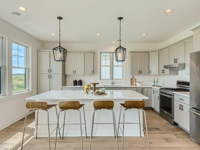 kitchen with a kitchen island, appliances with stainless steel finishes, hanging light fixtures, and sink