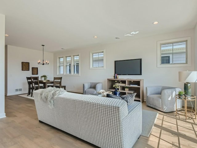 living room with light hardwood / wood-style floors, an inviting chandelier, and a healthy amount of sunlight