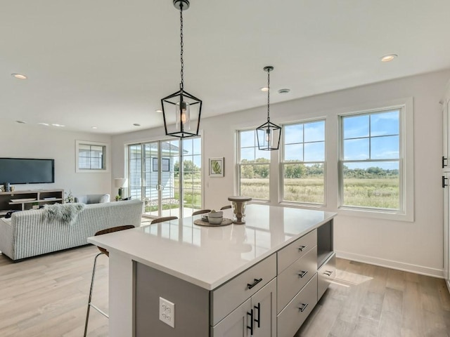 kitchen with a kitchen island, light hardwood / wood-style floors, a breakfast bar, and hanging light fixtures