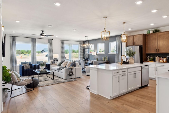 kitchen with sink, white cabinetry, ceiling fan, an island with sink, and hanging light fixtures