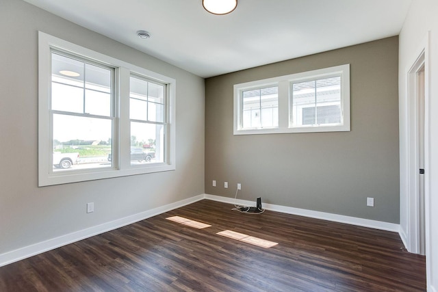 empty room with a healthy amount of sunlight and dark hardwood / wood-style floors