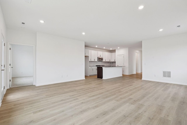 unfurnished living room with sink and light wood-type flooring