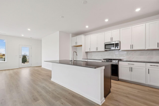 kitchen featuring stainless steel appliances, white cabinets, sink, and a kitchen island with sink