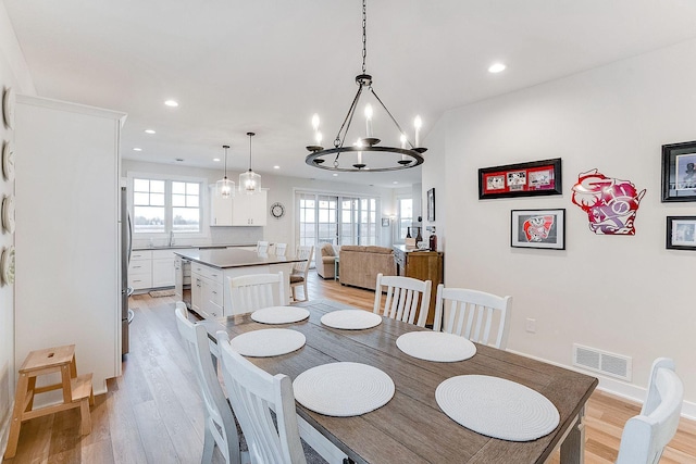 dining area with light hardwood / wood-style flooring, a chandelier, and sink