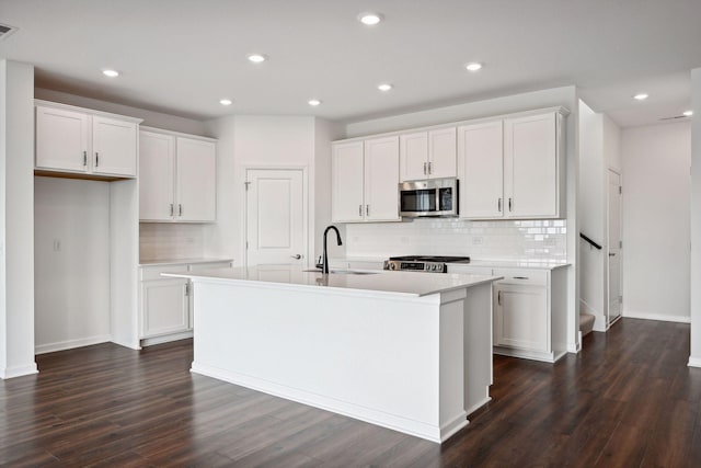 kitchen featuring white cabinets, sink, a center island with sink, and stove