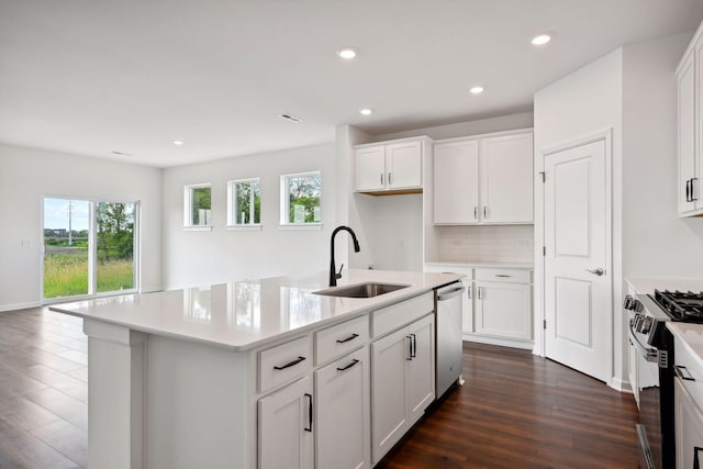 kitchen with sink, appliances with stainless steel finishes, white cabinets, a center island with sink, and dark wood-type flooring