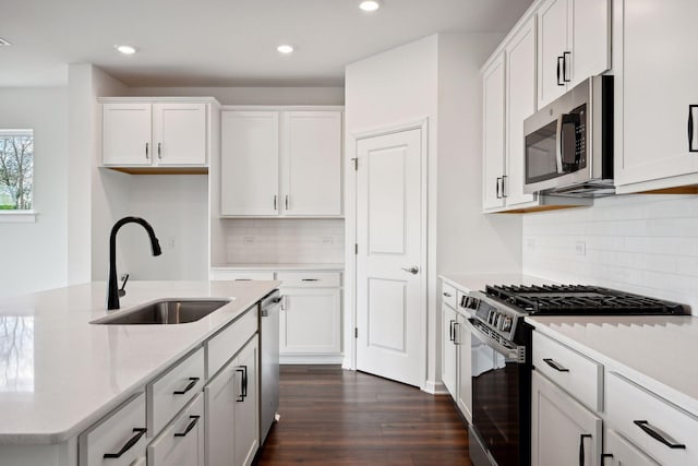 kitchen with stainless steel appliances, sink, white cabinets, decorative backsplash, and dark wood-type flooring