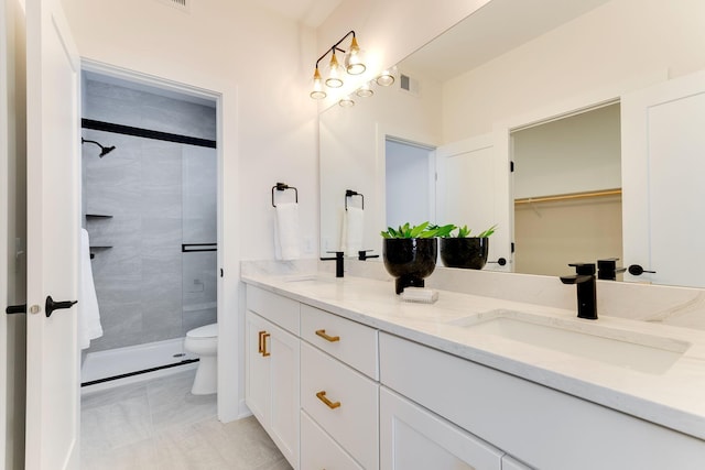 bathroom with toilet, tile patterned floors, tiled shower, and vanity