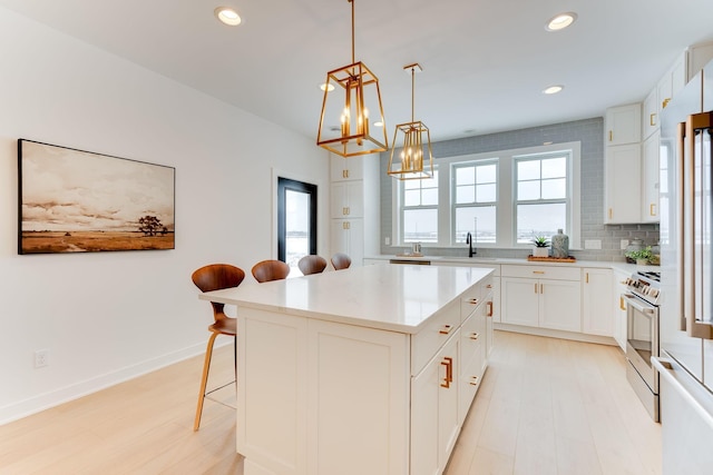 kitchen featuring a breakfast bar area, a center island, stainless steel stove, white cabinets, and tasteful backsplash