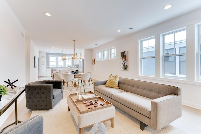 living room featuring light wood-type flooring, a notable chandelier, and plenty of natural light