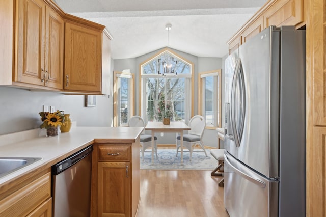 kitchen featuring light hardwood / wood-style floors, kitchen peninsula, appliances with stainless steel finishes, a notable chandelier, and vaulted ceiling