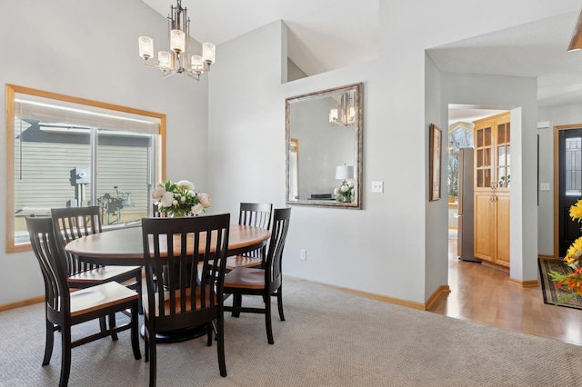 carpeted dining room with plenty of natural light, lofted ceiling, and an inviting chandelier