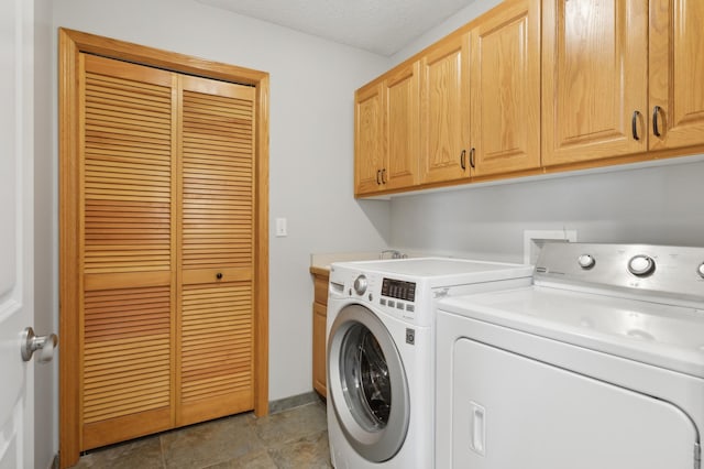 laundry room with cabinets, a textured ceiling, and washer and clothes dryer