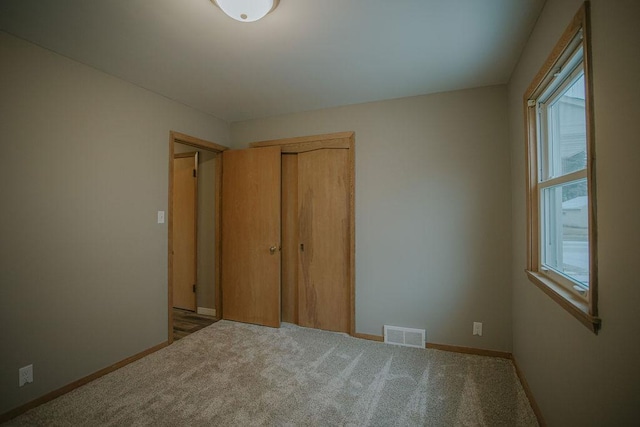 unfurnished bedroom with light colored carpet and a closet