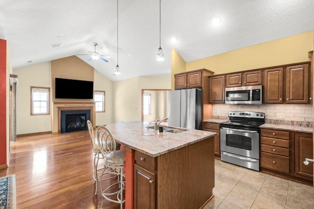 kitchen featuring backsplash, sink, appliances with stainless steel finishes, a kitchen breakfast bar, and an island with sink