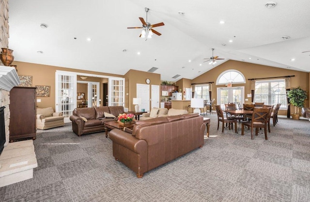 carpeted living room with ceiling fan, vaulted ceiling, french doors, and a fireplace