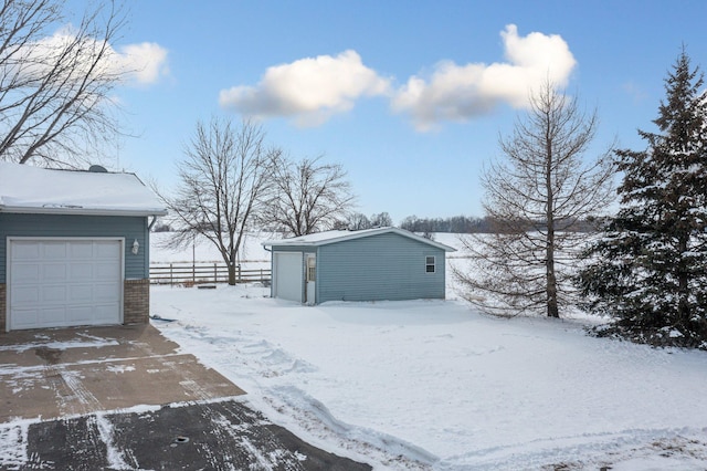 yard covered in snow featuring an outbuilding and a garage