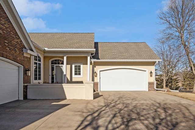 view of front of house with a garage, brick siding, a shingled roof, and stucco siding