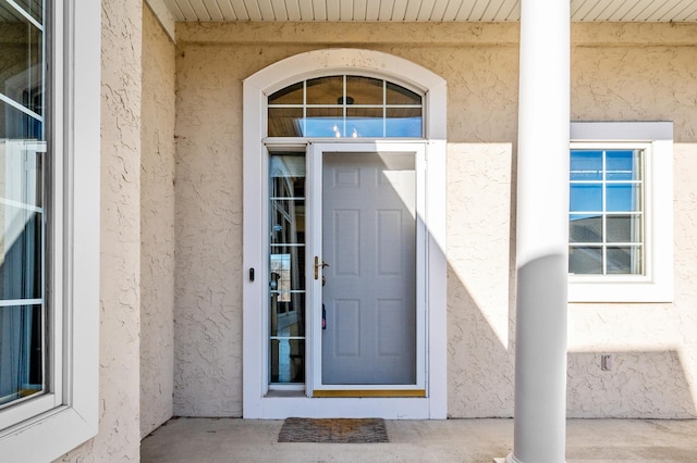 doorway to property featuring stucco siding