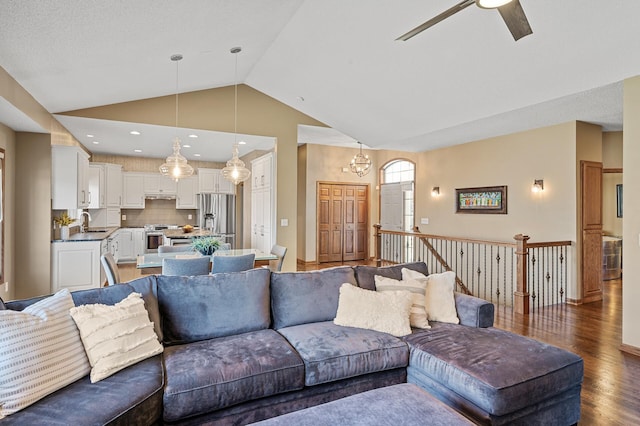 living room with light wood-style flooring, baseboards, vaulted ceiling, and ceiling fan with notable chandelier