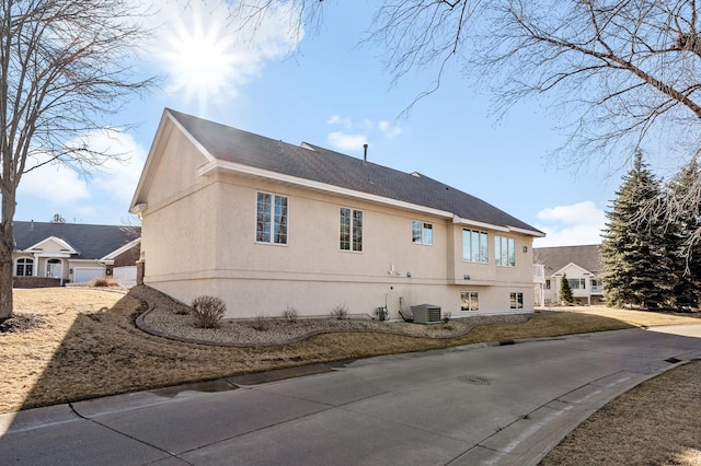 view of side of home featuring central AC and stucco siding