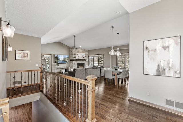 hallway with vaulted ceiling, wood finished floors, visible vents, and baseboards