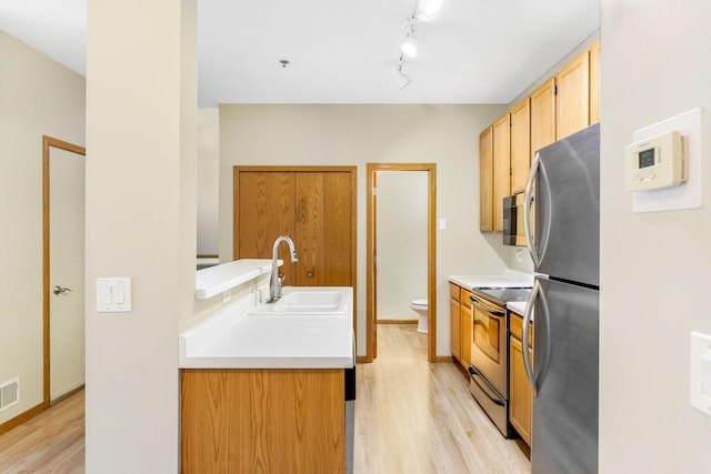 kitchen with light hardwood / wood-style floors, stainless steel appliances, track lighting, light brown cabinets, and sink