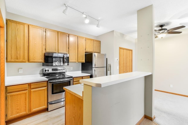 kitchen with ceiling fan, light brown cabinetry, light wood-type flooring, and appliances with stainless steel finishes