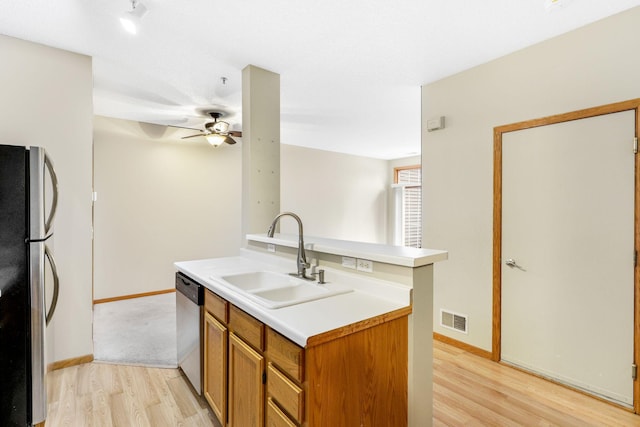 kitchen featuring stainless steel appliances, sink, ceiling fan, and light wood-type flooring