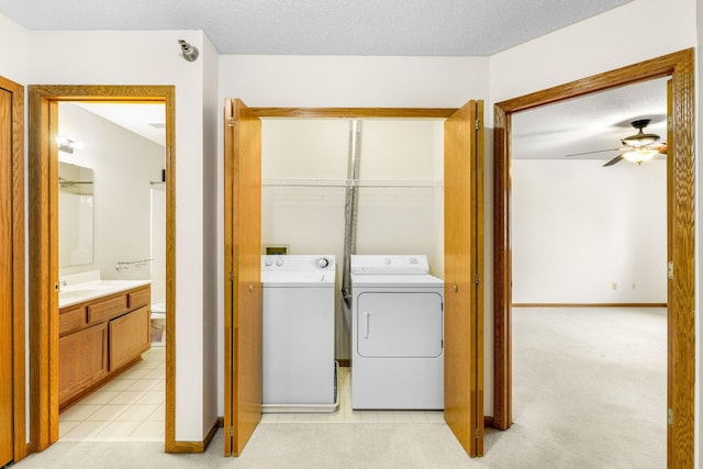 washroom with light tile patterned floors, ceiling fan, a textured ceiling, sink, and washing machine and clothes dryer