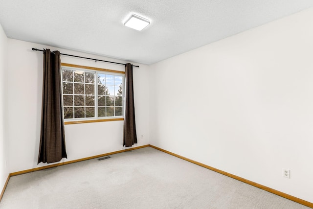 carpeted empty room featuring a textured ceiling