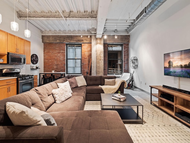 living room with brick wall, track lighting, and beamed ceiling