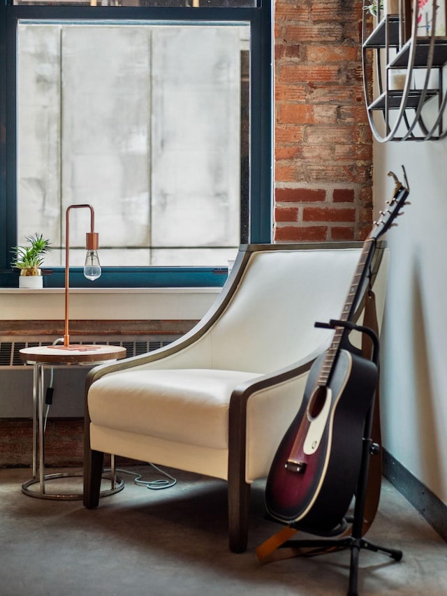 living area featuring brick wall and concrete flooring