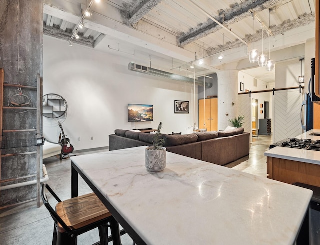 dining area with rail lighting, a barn door, and concrete flooring