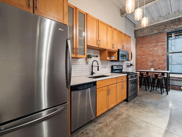 kitchen with brick wall, appliances with stainless steel finishes, decorative light fixtures, tasteful backsplash, and sink