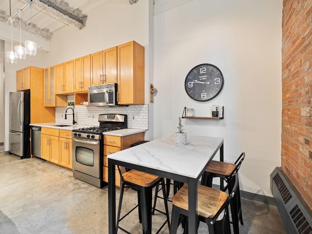 kitchen featuring decorative light fixtures, beam ceiling, appliances with stainless steel finishes, and a towering ceiling