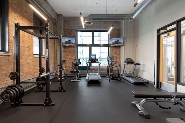 workout area featuring a high ceiling and brick wall