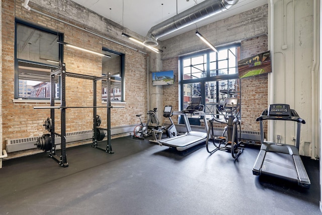 workout area featuring brick wall and a high ceiling