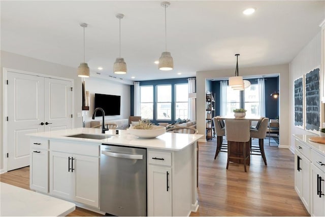 kitchen featuring pendant lighting, dishwasher, white cabinetry, sink, and a center island with sink