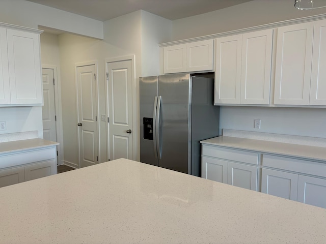 kitchen featuring white cabinets, light stone counters, and stainless steel refrigerator with ice dispenser