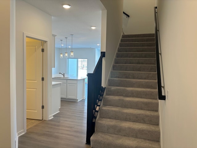 staircase with wood finished floors and recessed lighting