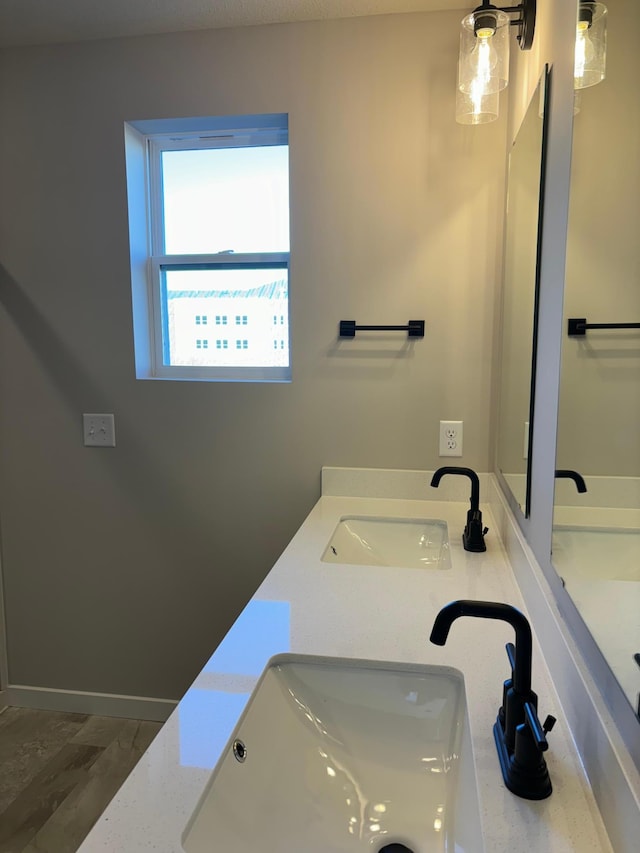 bathroom featuring double vanity, baseboards, and a sink