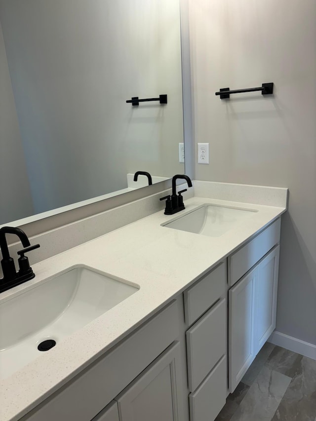 bathroom with marble finish floor, double vanity, and a sink