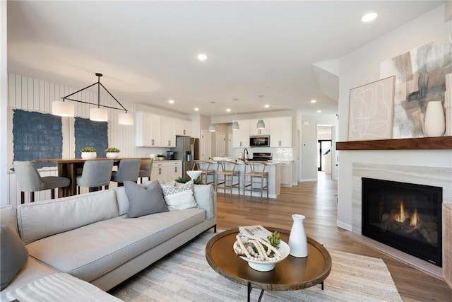 living room featuring light wood-type flooring, a warm lit fireplace, and recessed lighting