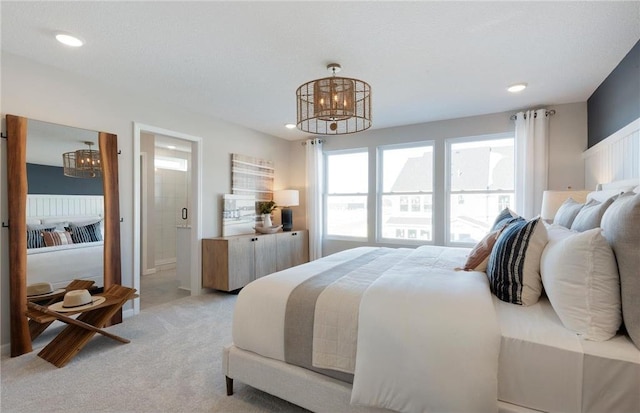 bedroom featuring recessed lighting, light carpet, ensuite bath, and an inviting chandelier