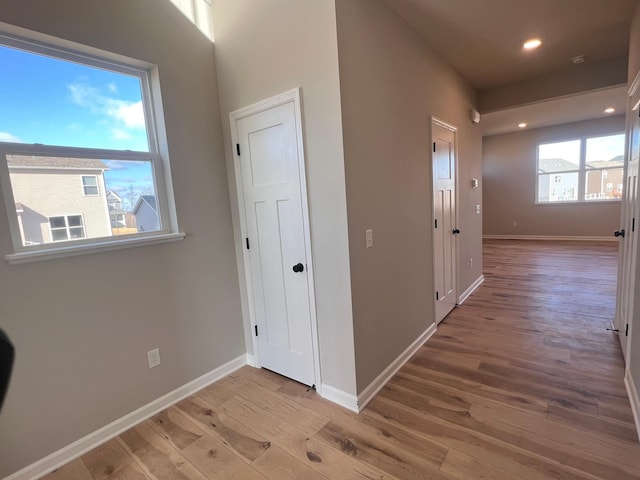 hall with light wood-style floors, baseboards, and recessed lighting