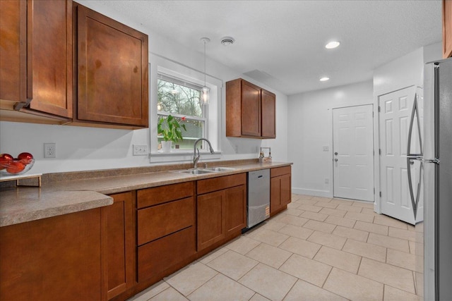 239 1st St, New Richmond, WI 54017 - kitchen featuring decorative light fixtures, brown cabinets, a sink, stainless steel appliances, and light tile patterned flooring