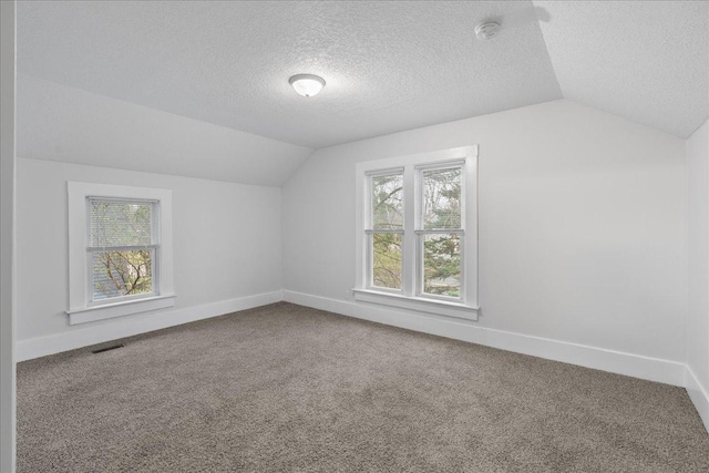 239 1st St, New Richmond, WI 54017 - bonus room featuring a textured ceiling, carpet, baseboards, lofted ceiling, and visible vents