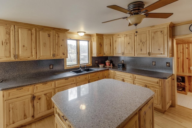 kitchen featuring a kitchen island, light hardwood / wood-style floors, backsplash, and sink